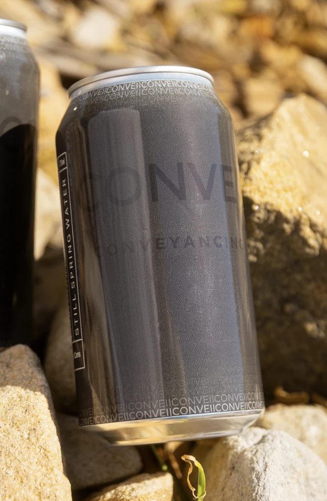A Conveii Conveyancing branded can on rocks